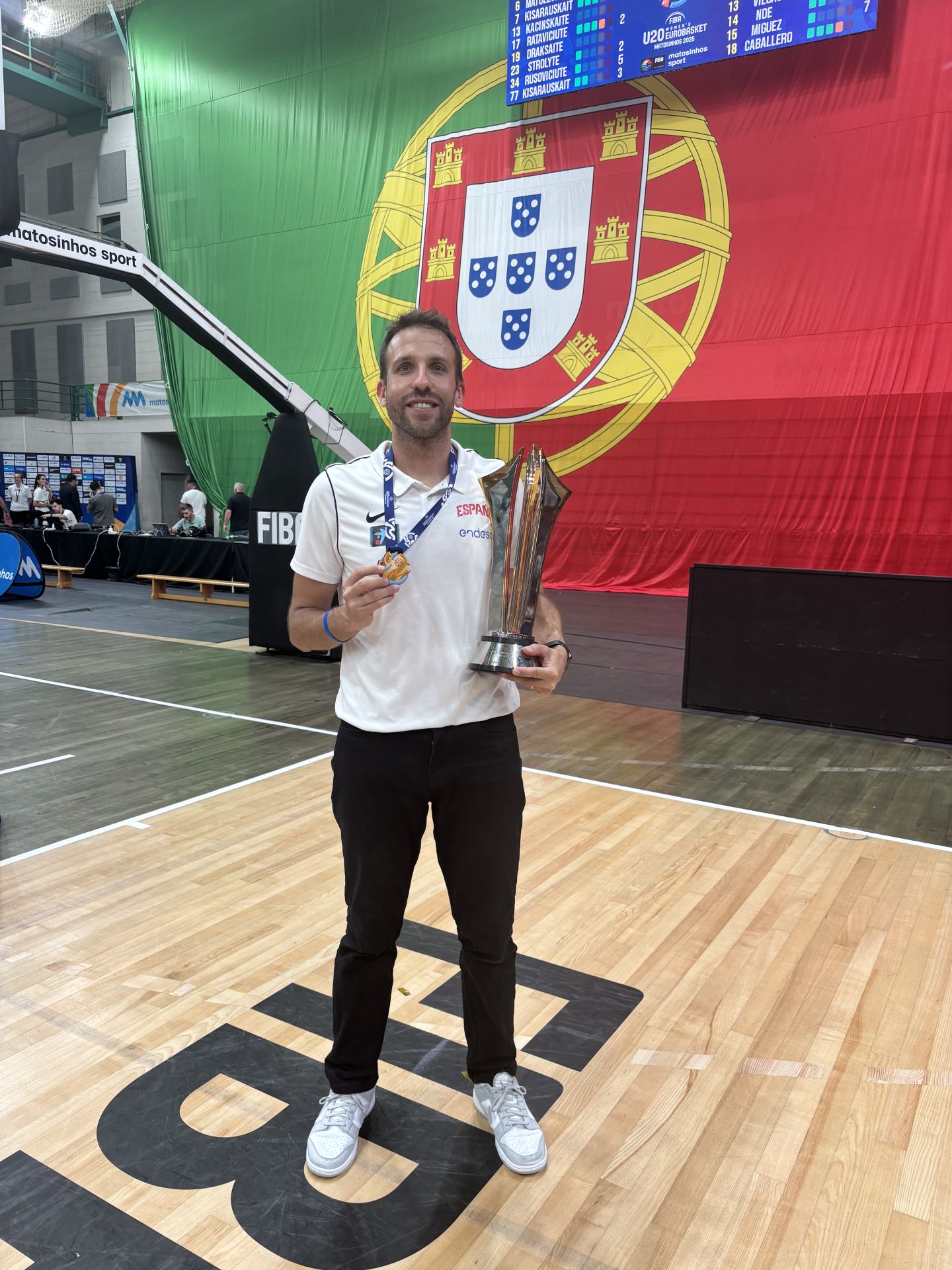 Álex Gómez sostiene exultante con la copa y la medalla conseguidas en su debut con España.