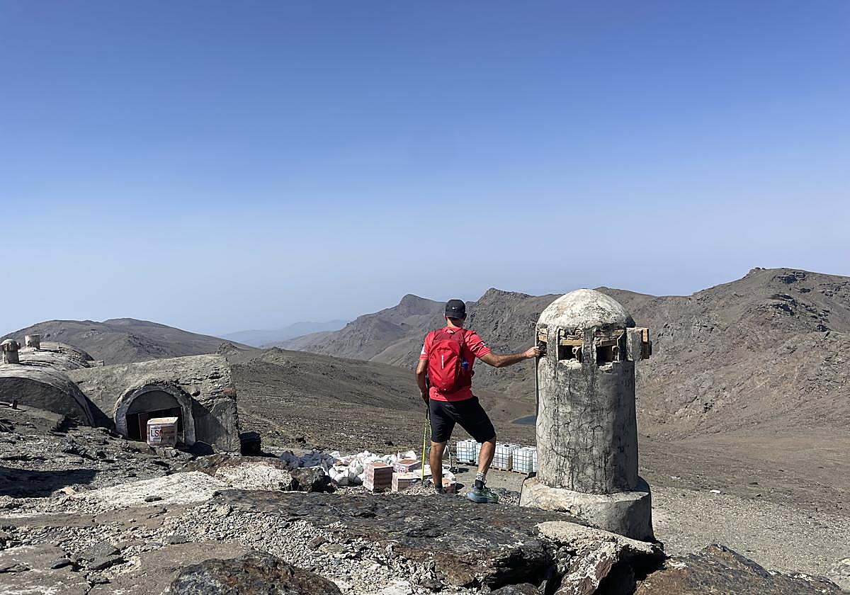 Un montañero junto a una de las chimeneas del refugio y, al fondo, los materiales de obra.