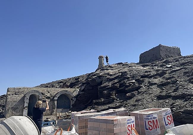 Un montañero hace fotos a su compañero junto a la chimenea, entre los materiales de obra.