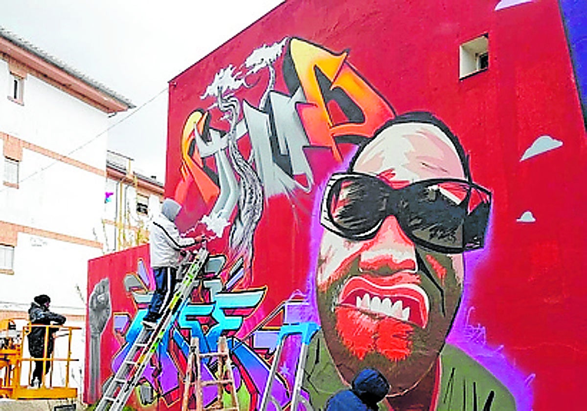 Imagen principal - Icat y David Stone con su compinche pintan sus murales en diversos pueblos de Granada.