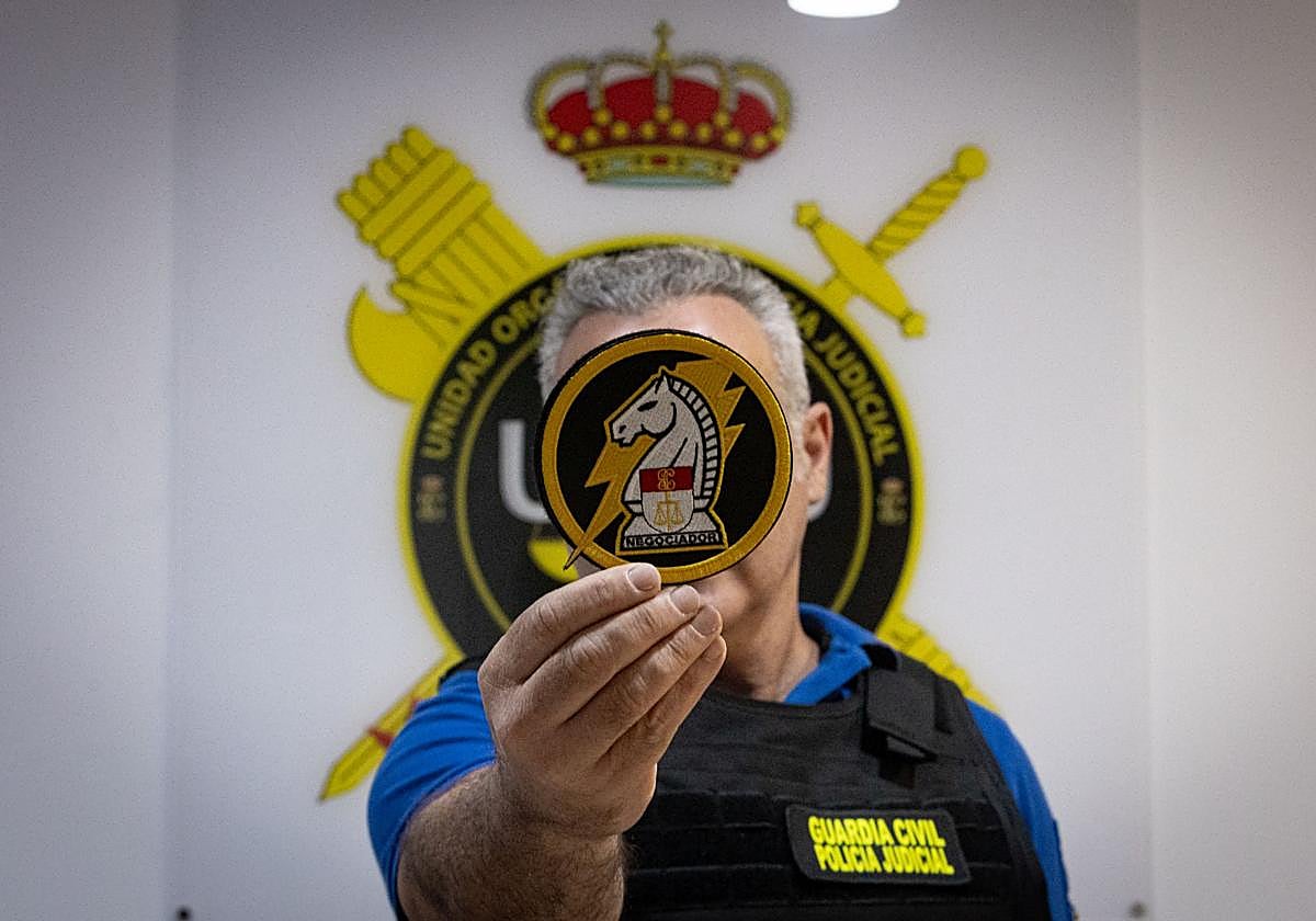 Uno de los dos negociadores de la Guardia Civil sostiene el nuevo escudo, creado recientemente.