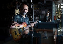 Quini Almendros posa con una de las cien guitarras que tiene en su negocio.