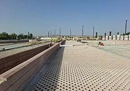 En primer plano, el pavimento del aparcamiento de La Gloria junto a las vías del metro y al fondo, los postes de catenaria.