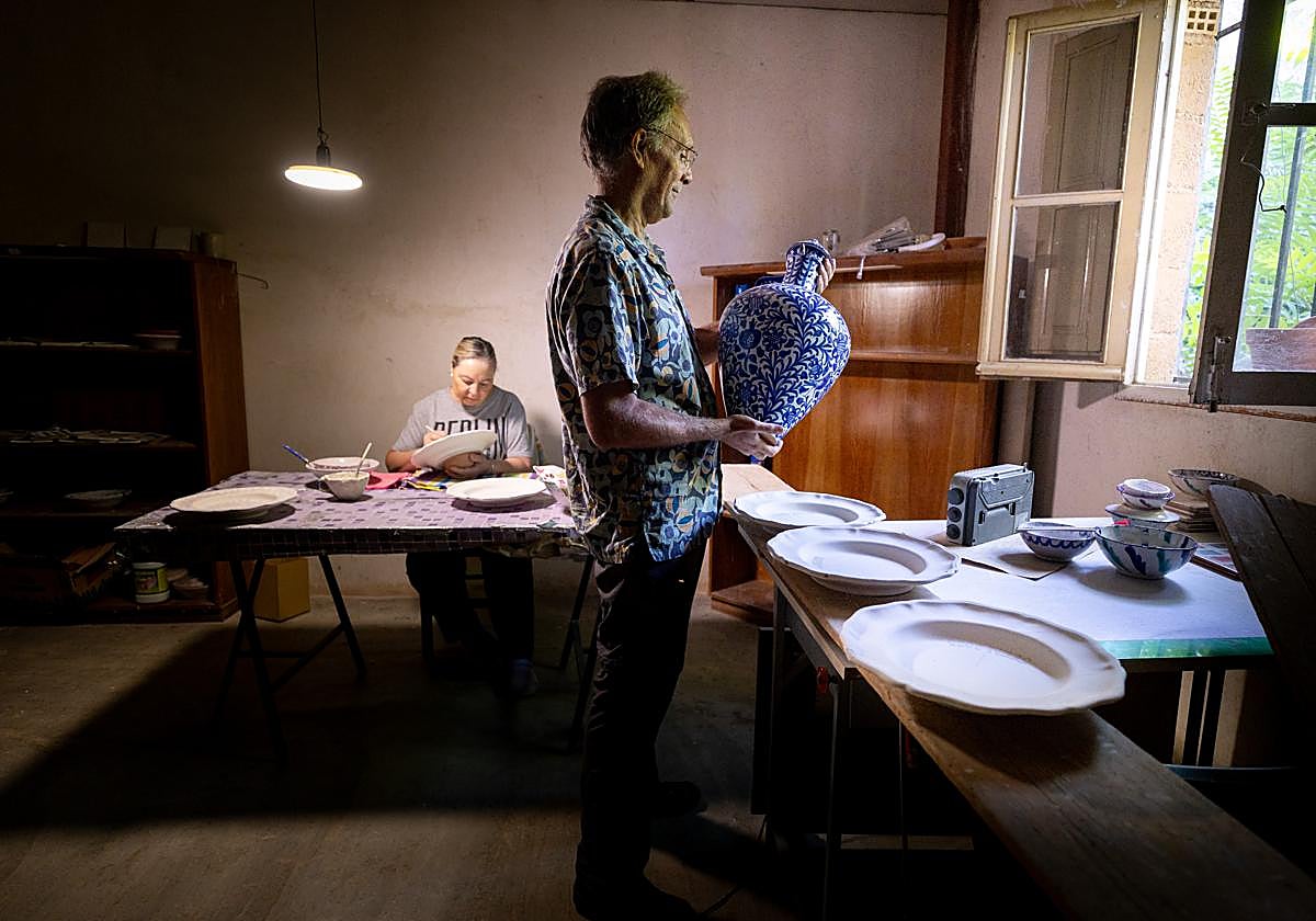 Chemi Márquez observa un jarrón elaborado en la fábrica mientras Encarna, una voluntaria, decora una pieza