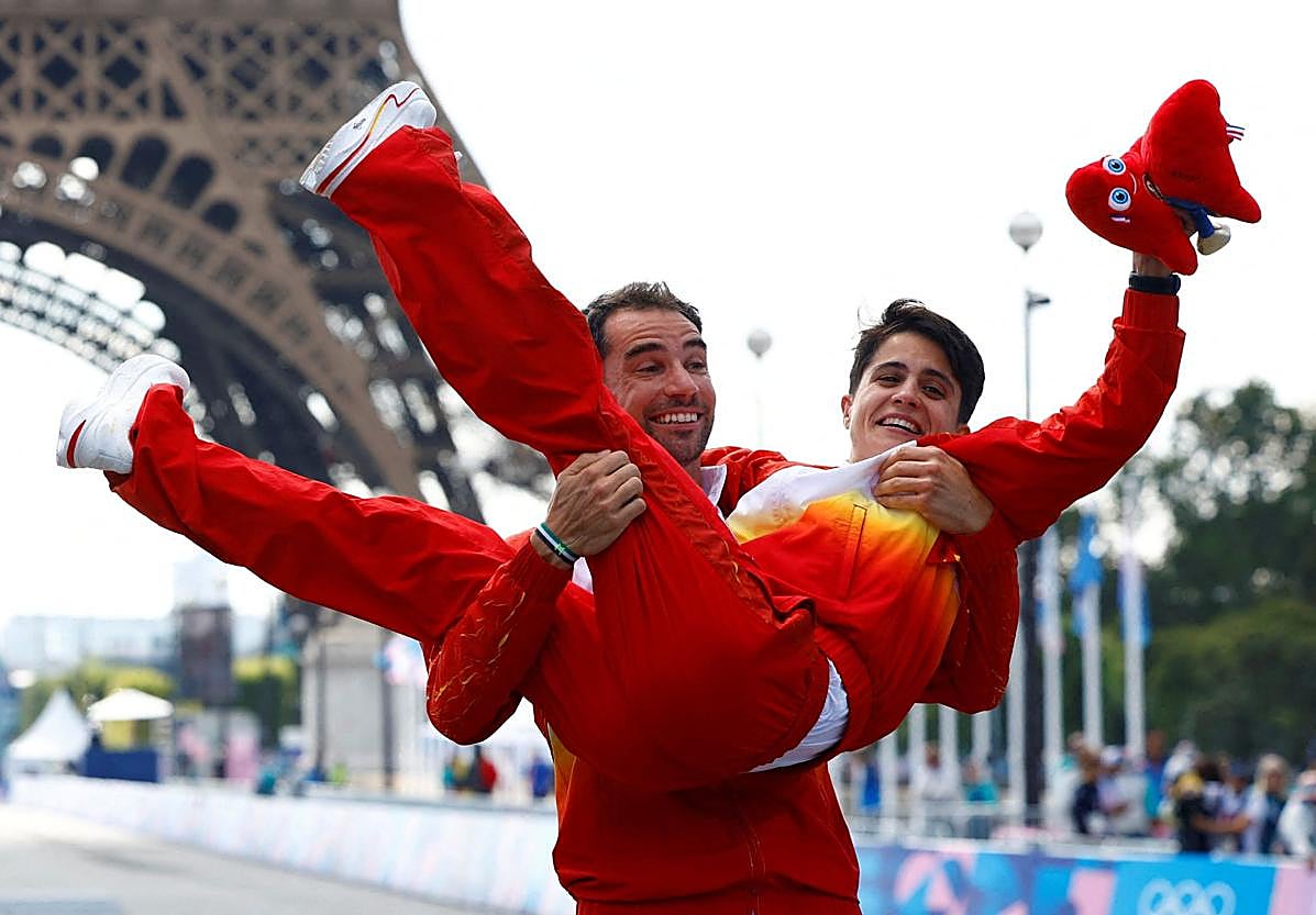 Gloria en París. Álvaro Martín eleva a María Pérez tras ganar conjuntamenteel relevo mixto de marcha.