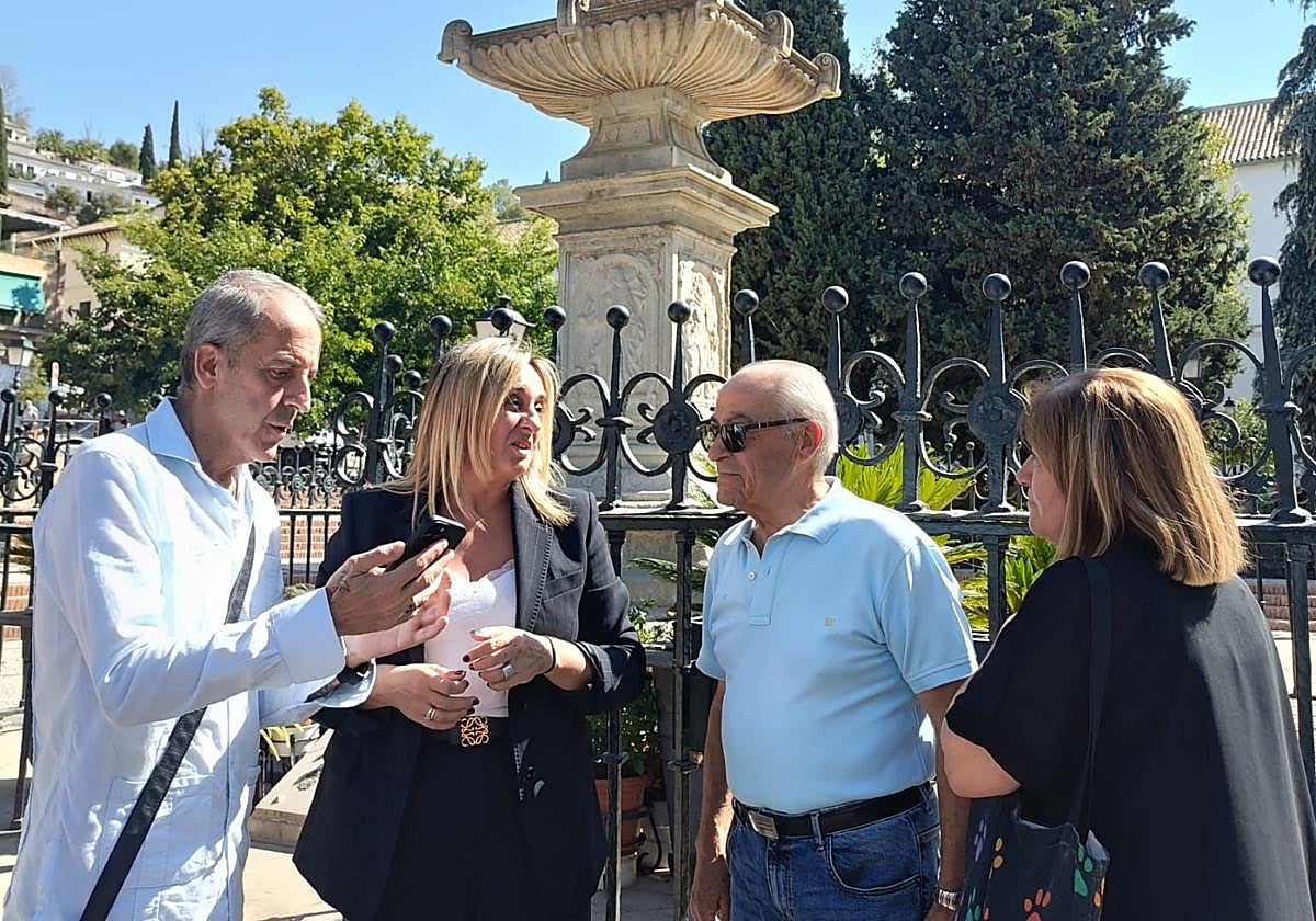 La alcaldesa de Granada, flanqueada por el presidente de la asociación del Realejo y un hermano de los Favores, escucha a una vecina.