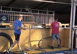 Dos operarios montan una caseta en el recinto ferial.
