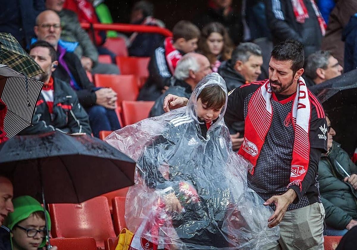 Aficionados del Granada se resguardan de la lluvia durante un partido anterior en Los Cármenes.