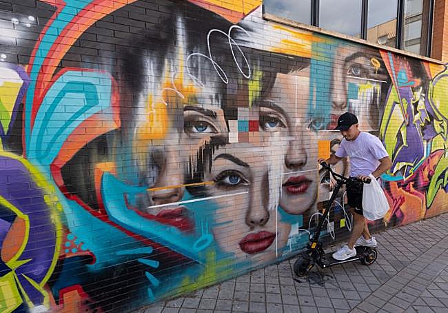 Chaval transitando en monopatín junto a mural en la Chana.