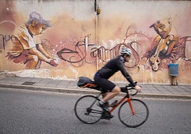 Ciclista pasa por delante de un mural en el barrio del Realejo.