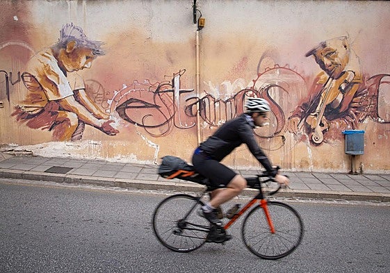 Ciclista pasa por delante de un mural en el barrio del Realejo.