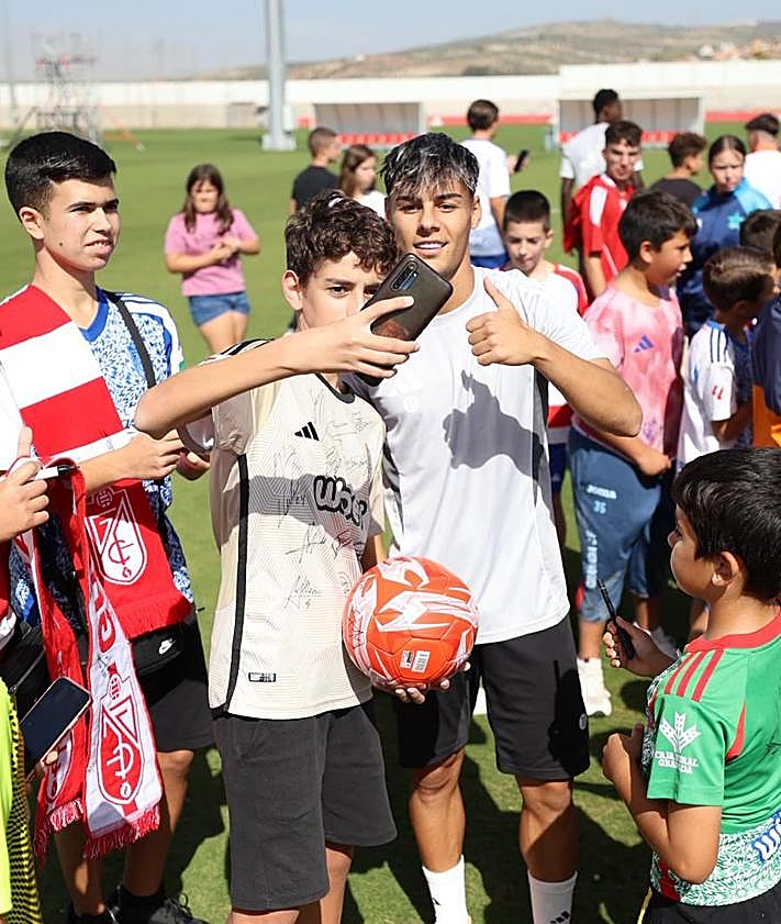 Imagen secundaria 2 - Arriba, posado de los más pequeños mezclados con el equipo. Debajo, Pablo Saénz firma una bandera a la izquierda y Samu Cortés posa para una foto a la derecha. 