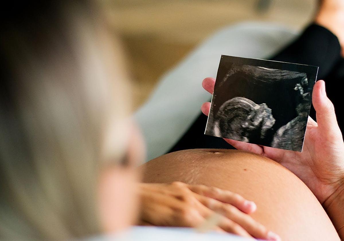 Una mujer embarazada contempla una ecografía del feto.