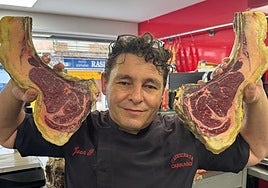 Juan Pedro con unos chuletones en su carnicería.