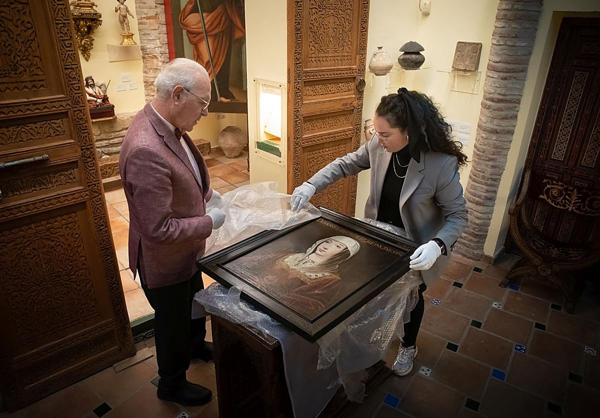 Carlos Ballesta y María Esperanza Pérez desenvuelven el cuadro de Isabel la Católica que ha adquirido la Fundación.