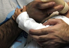 Un hombre da el biberón a su hijo.