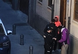 Una patrulla de la Policía Nacional identifica a dos personas en la puerta de la casa de acogida de la calle Varela.