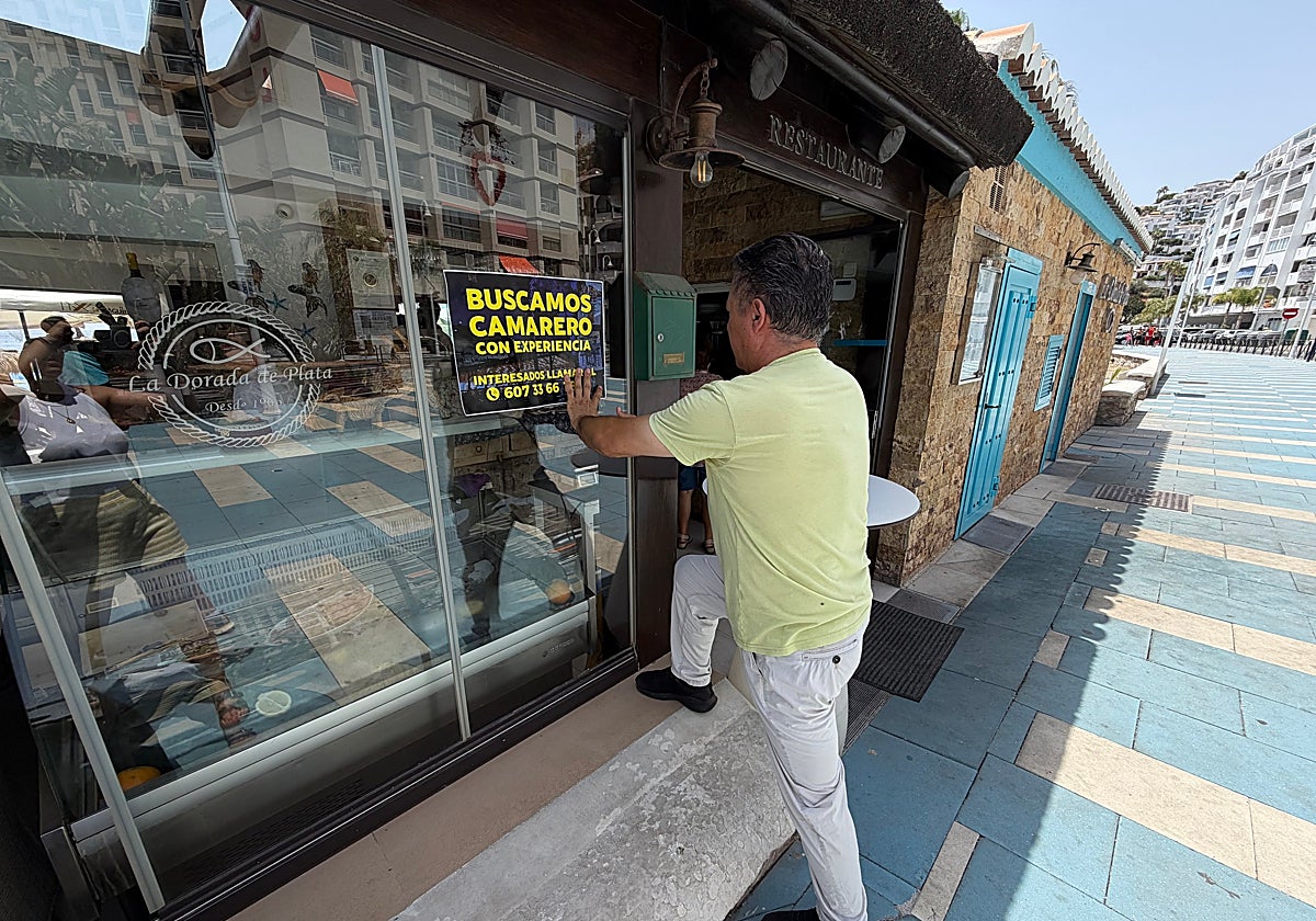 Francisco Mingorance, propietario del chiringuito La Dorada de Plata de Almuñécar coloca un cartel en el que se busca camarero.