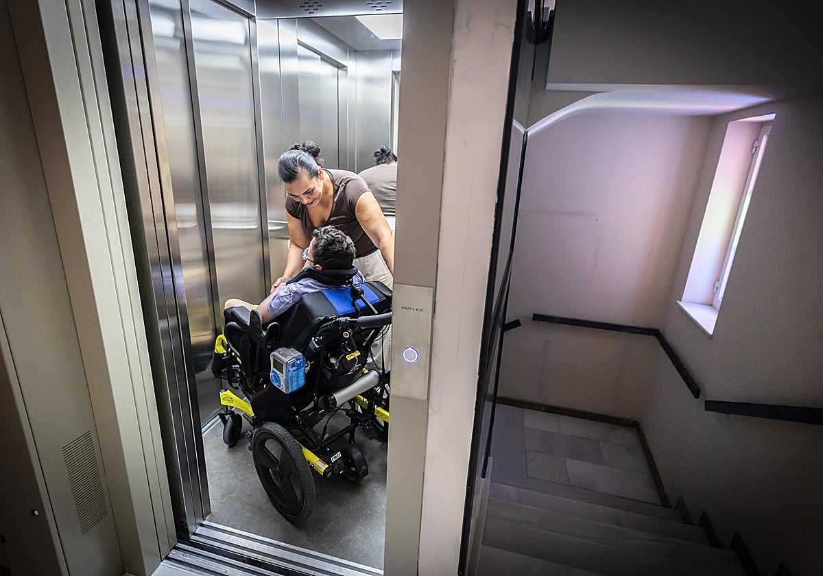 María habla con su hijo Javier, sentado en su especial silla de ruedas, en el interior del ascensor, recientemente instalado.