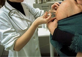 Una sanitaria vacuna a una mujer.