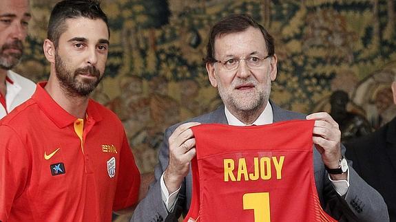 Rajoy (d) muestra la camiseta que le regaló la FEB. 
