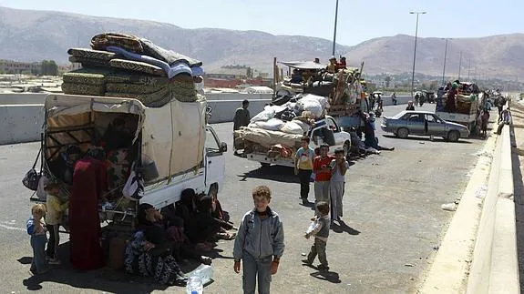 Varios refugiados sirios esperan junto a sus pertenencias en la frontera libanesa cerca del valle Bekaa (Líbano). 