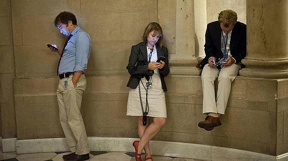 Periodistas norteamericanos miran sus smartphones en el Capitolio. 