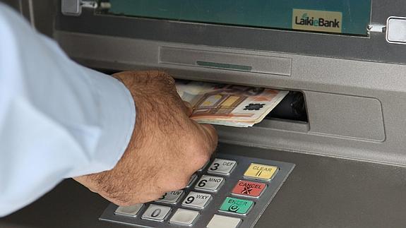 Un hombre saca dinero de un cajero automático. 