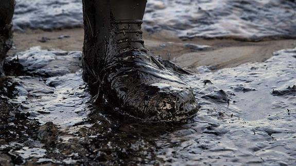 El petróleo cubre las botas de un hombre en Santa Bárbara. 