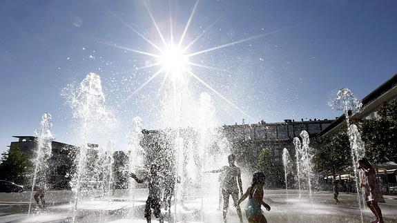 Un grupo de jóvenes disfrutan del baño con unos chorros de agua en el parque de Yamaguchi en Pamplona. 