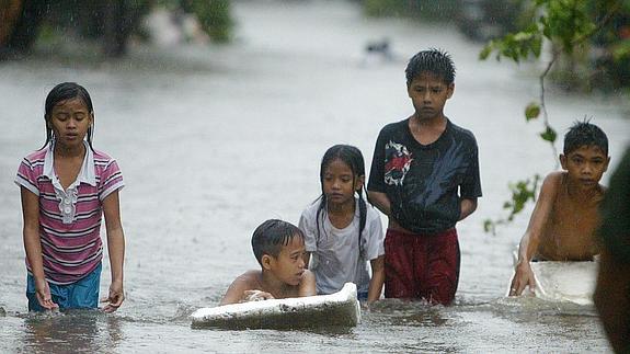 Varios niños caminan entre las aguas debido a las inundaciones provocadas en Filipinas por el tifón Koppu.