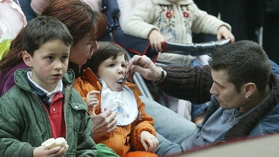 Un hombre da de comer a su hijo pequeño en la calle.