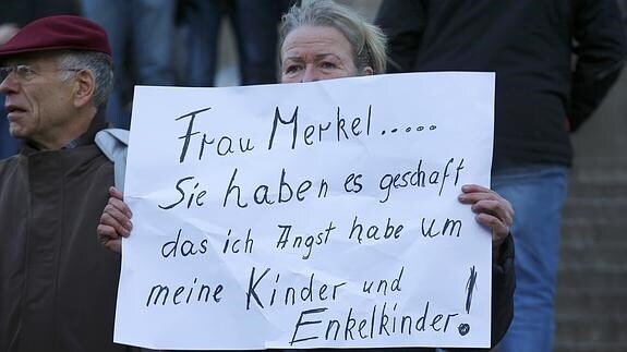 Una mujer muestra un cartel con un mensaje a Merkel durante una concentración organizada por Pegida. 
