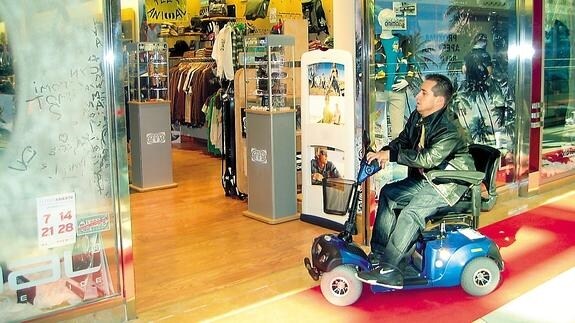 'El Langui', en una silla de ruedas motorizadas por un centro comercial.