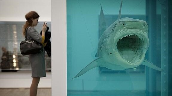 Una mujer fotografía un tiburón disecado, obra del artista Damien Hirst. 