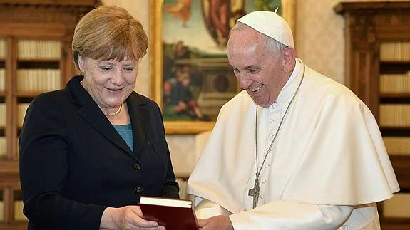 El papa Francisco habla con Angela Merkel antes de recibir el galardón. 