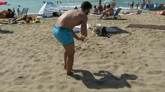 Bañista recoge colillas en la playa de Castelldefells.