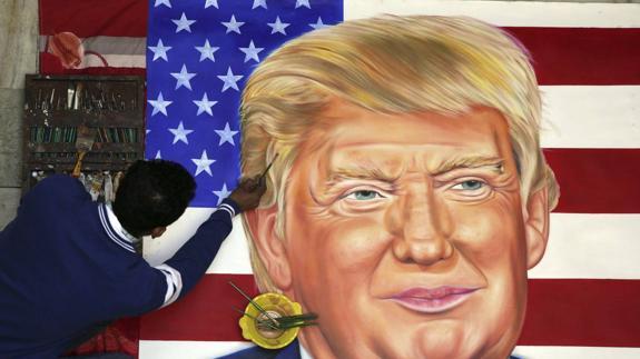 Un artista callejero pinta un retrato de Donald Trump.