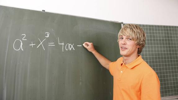 Un joven escribe una ecuación en la pizarra. 