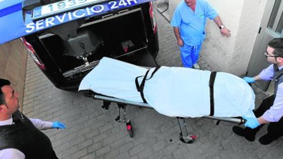 Empleados de la funeraria sacan del hospital una camilla con el cuerpo de Juan Carlos M.P. 