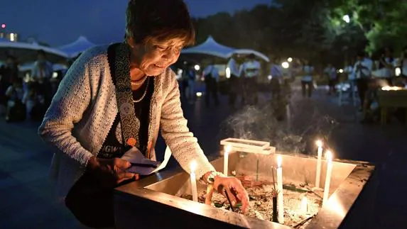 Una mujer enciende una vela en homenaje a las víctimas de Hiroshima.
