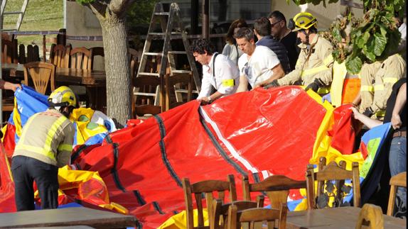 Varios operarios y bomberos retiran el castillo hinchable.