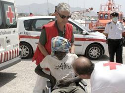 Miembros de la Cruz Roja atienden a uno de los inmigrantes subsaharianos que intentaban entrar en España en una patera interceptada en la costa granadina. EFE/PAQUET