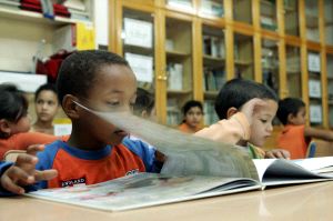 LENGUAJE. Unos niños miran un libro en una biblioteca escolar, donde se familiarizan con el español. / IDEAL