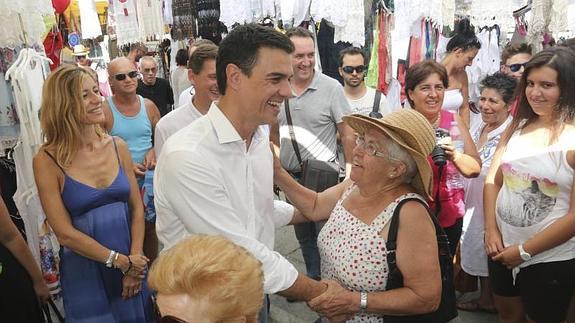 El secretario general del PSOE, Pedro Sánchez , acompañado de su esposa, Begoña Fernández (i) saluda a una señora en un mercadillo de la localidad almeriense de Mojácar donde pasa unos días de vacaciones  