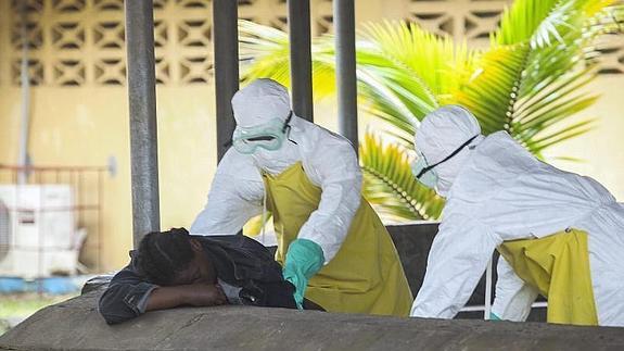 Dos enfermeros se diponen a trasladar el cuerpo de una fallecida por ébola 