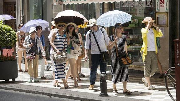 Turistas se protegen del sol con un paraguas en la capital 