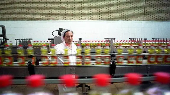 Operario controla la cadena de envasado de las botellas de aceite.