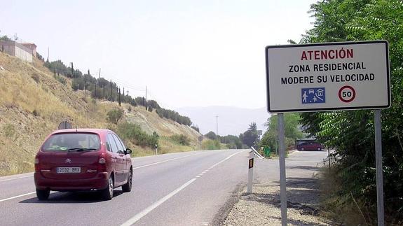 Un vehículo circula por la N-323, ante un cartel que avisa de que se trata de una zona residencial.
