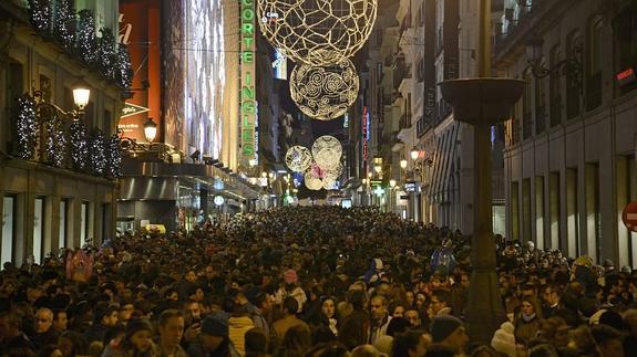 Una céntrica calle de Madrid llena de gente que realiza sus compras navideñas.